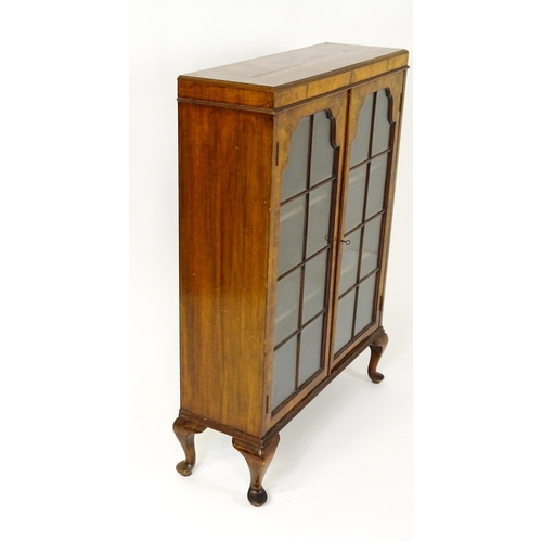 1545 - An early / mid 20thC walnut glazed display cabinet with two astragal glazed doors raised on four cab... 