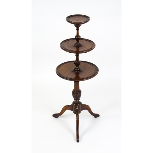 1550 - A 20thC three tier mahogany dumb waiter , with three graduated tiers above a turned pedestal with tw... 