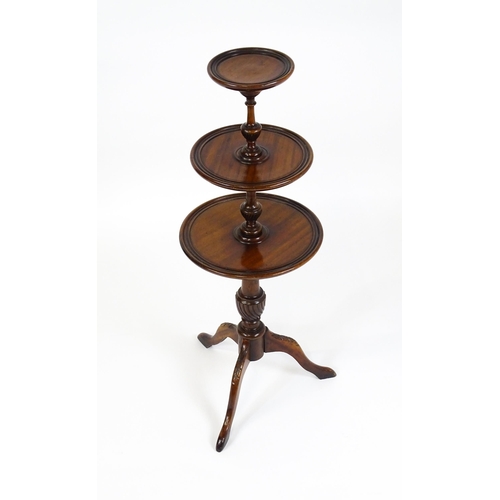 1550 - A 20thC three tier mahogany dumb waiter , with three graduated tiers above a turned pedestal with tw... 