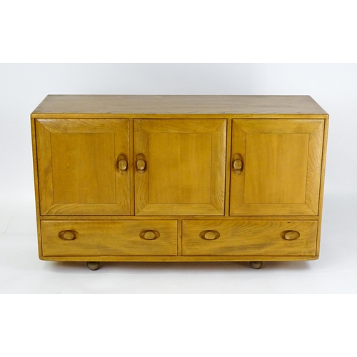 1629 - Vintage / Retro: An elm Ercol sideboard with a three panelled doors above two long drawers and raise... 