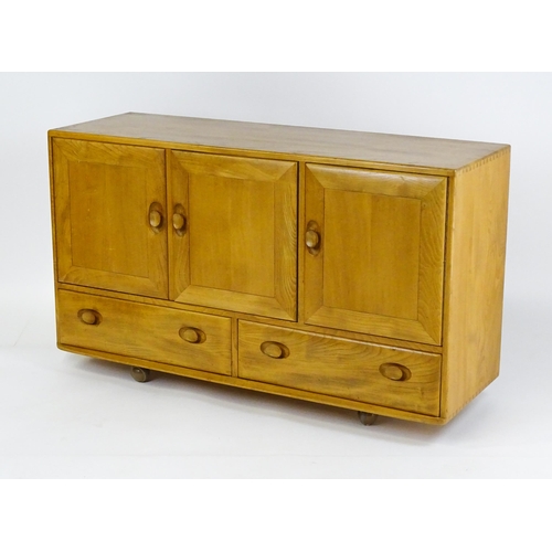 1629 - Vintage / Retro: An elm Ercol sideboard with a three panelled doors above two long drawers and raise... 