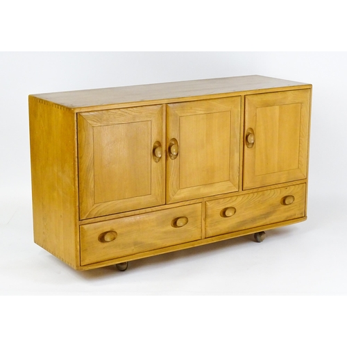 1629 - Vintage / Retro: An elm Ercol sideboard with a three panelled doors above two long drawers and raise... 