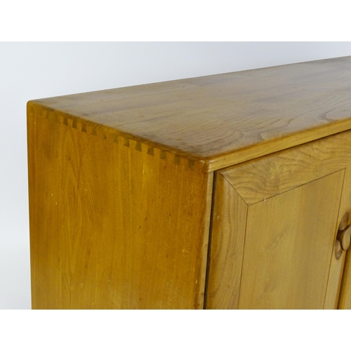 1629 - Vintage / Retro: An elm Ercol sideboard with a three panelled doors above two long drawers and raise... 