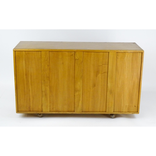 1629 - Vintage / Retro: An elm Ercol sideboard with a three panelled doors above two long drawers and raise... 