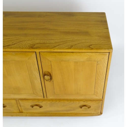 1629 - Vintage / Retro: An elm Ercol sideboard with a three panelled doors above two long drawers and raise... 