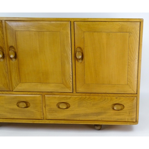 1629 - Vintage / Retro: An elm Ercol sideboard with a three panelled doors above two long drawers and raise... 