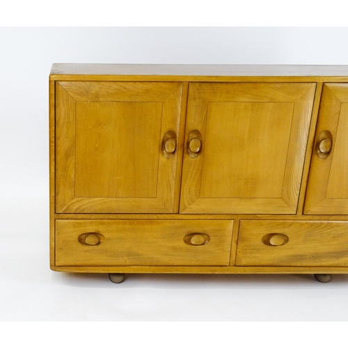 1629 - Vintage / Retro: An elm Ercol sideboard with a three panelled doors above two long drawers and raise... 