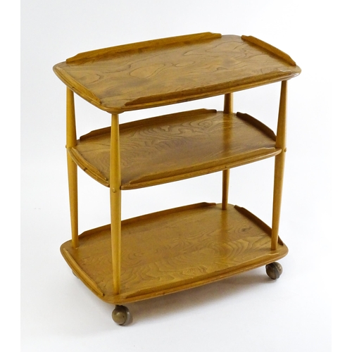 1630 - Vintage / Retro : An elm Ercol three tier trolley with shaped upstands, and turned uprights raised o... 