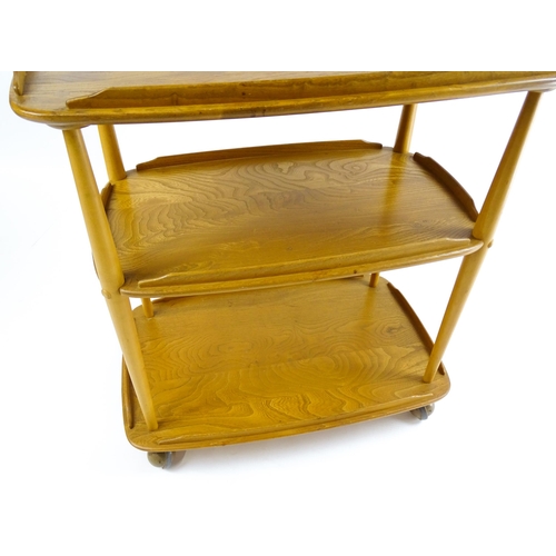 1630 - Vintage / Retro : An elm Ercol three tier trolley with shaped upstands, and turned uprights raised o... 