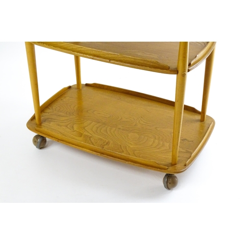 1630 - Vintage / Retro : An elm Ercol three tier trolley with shaped upstands, and turned uprights raised o... 