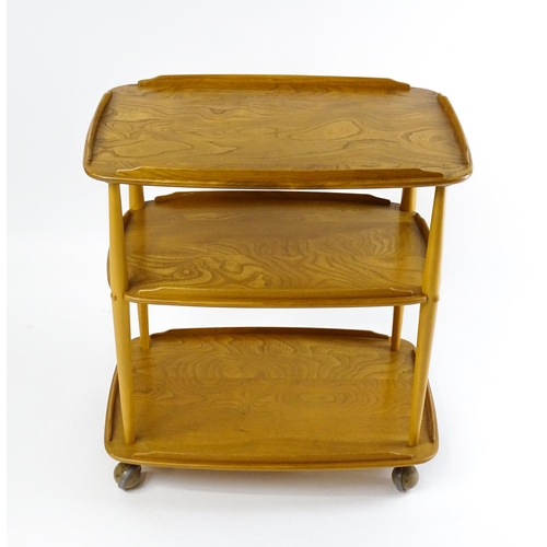 1630 - Vintage / Retro : An elm Ercol three tier trolley with shaped upstands, and turned uprights raised o... 