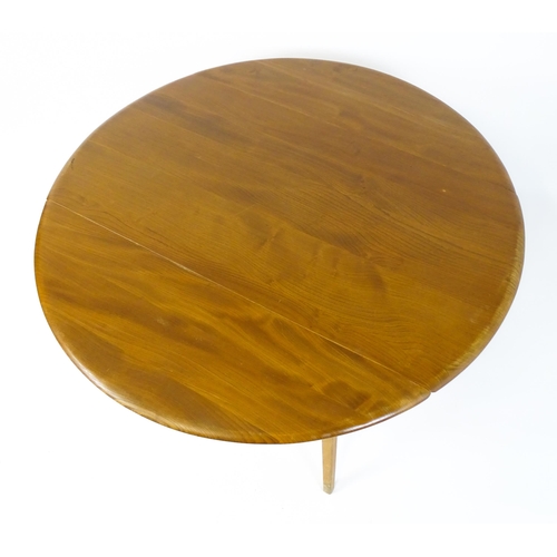 1631 - Vintage / Retro: An elm Ercol drop flap table with two demi lune leaves raised on four tapering legs... 