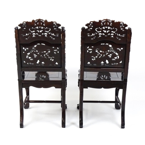 1452 - A pair of late 19thC / early 20thC Chinese hardwood side chairs with intricately carved frames depic... 