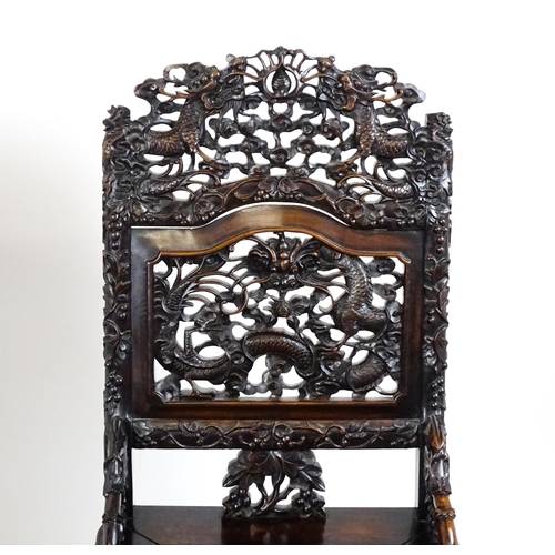 1452 - A pair of late 19thC / early 20thC Chinese hardwood side chairs with intricately carved frames depic... 