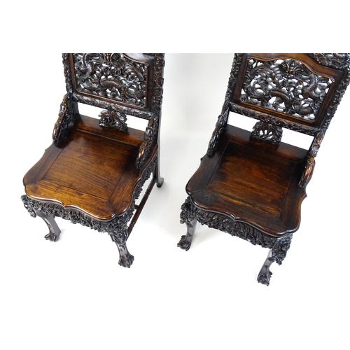 1452 - A pair of late 19thC / early 20thC Chinese hardwood side chairs with intricately carved frames depic... 