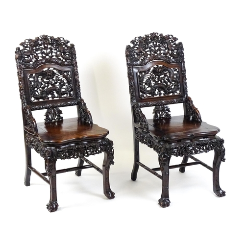 1452 - A pair of late 19thC / early 20thC Chinese hardwood side chairs with intricately carved frames depic... 