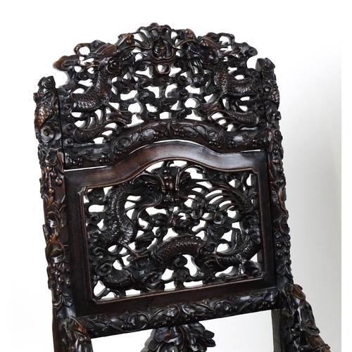 1452 - A pair of late 19thC / early 20thC Chinese hardwood side chairs with intricately carved frames depic... 