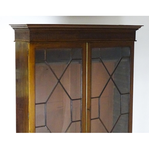 1503 - A late 19thC / early 20thC mahogany bookcase with a moulded fluted cornice above two astragal glazed... 