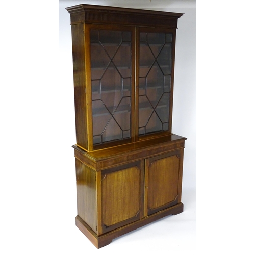 1503 - A late 19thC / early 20thC mahogany bookcase with a moulded fluted cornice above two astragal glazed... 