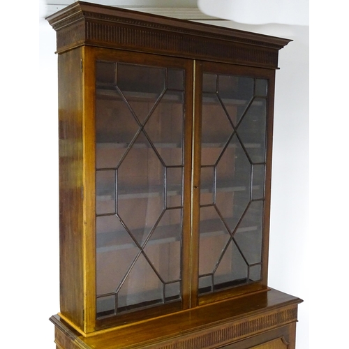 1503 - A late 19thC / early 20thC mahogany bookcase with a moulded fluted cornice above two astragal glazed... 