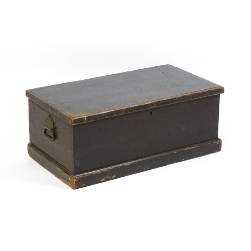 1615 - An early 19thC black painted pine trunk flanked by wrought iron carrying handles, the hinged lid ope... 