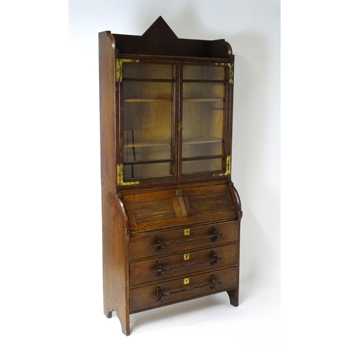 1480 - A late 19thC oak Arts & Crafts bureau bookcase with a pointed pediment above glazed doors and brass ... 