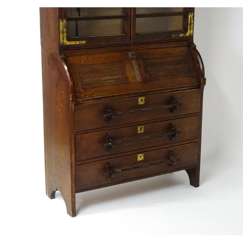 1480 - A late 19thC oak Arts & Crafts bureau bookcase with a pointed pediment above glazed doors and brass ... 