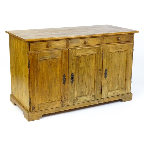 1494 - A 20thC pine sideboard with three short drawers above three panelled cupboard doors raised on bracke... 