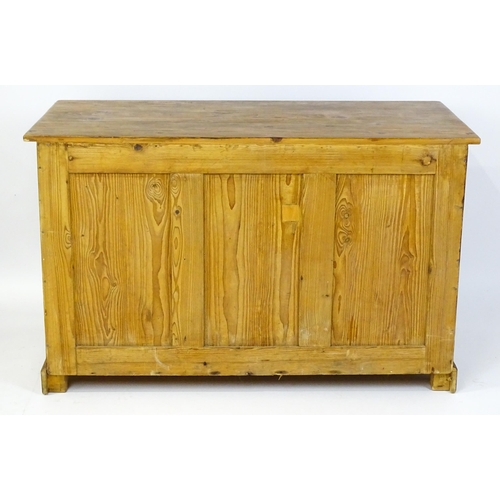 1494 - A 20thC pine sideboard with three short drawers above three panelled cupboard doors raised on bracke... 