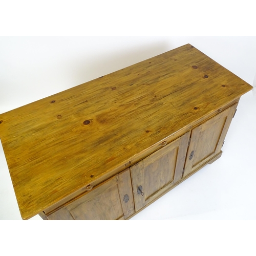 1494 - A 20thC pine sideboard with three short drawers above three panelled cupboard doors raised on bracke... 