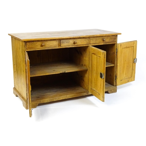 1494 - A 20thC pine sideboard with three short drawers above three panelled cupboard doors raised on bracke... 