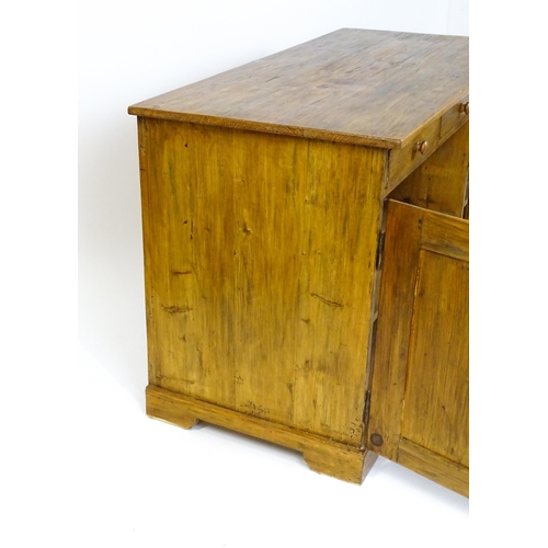 1494 - A 20thC pine sideboard with three short drawers above three panelled cupboard doors raised on bracke... 