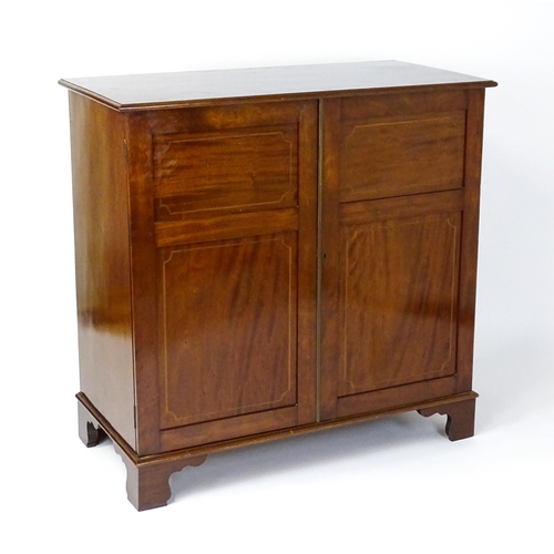 1498 - A mid 20thC mahogany cabinet with a moulded top above two panelled doors raised on ogee bracket feet... 