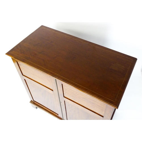 1498 - A mid 20thC mahogany cabinet with a moulded top above two panelled doors raised on ogee bracket feet... 