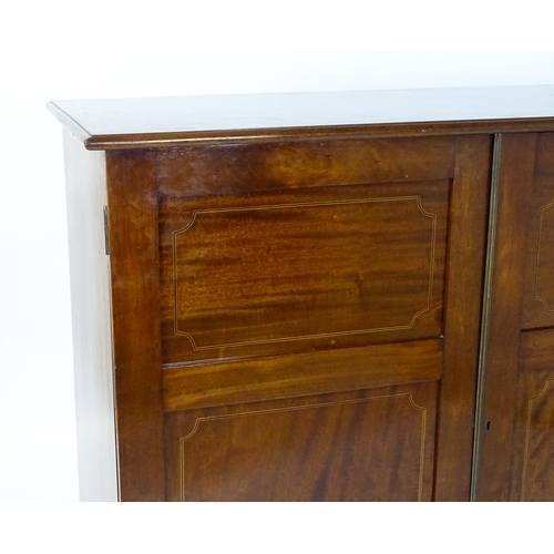 1498 - A mid 20thC mahogany cabinet with a moulded top above two panelled doors raised on ogee bracket feet... 