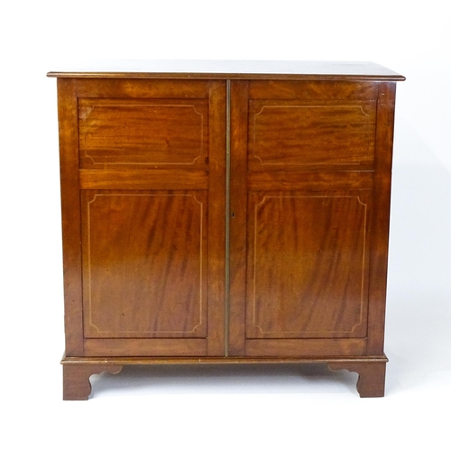 1498 - A mid 20thC mahogany cabinet with a moulded top above two panelled doors raised on ogee bracket feet... 