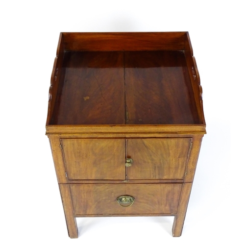 1522 - A Georgian mahogany tray top commode / bedside cabinet with pierced handles above two panelled doors... 