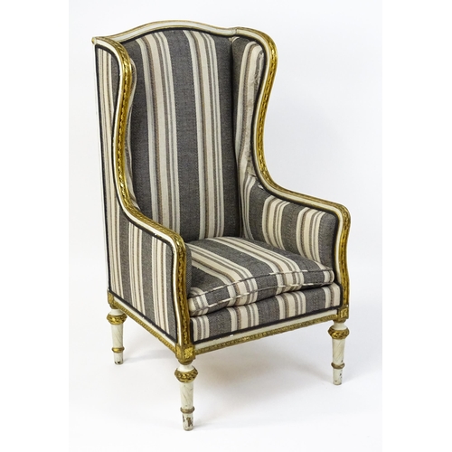 1557 - A Louis XVI style wingback armchair with a white and gold painted frame, striped upholstery and rais... 