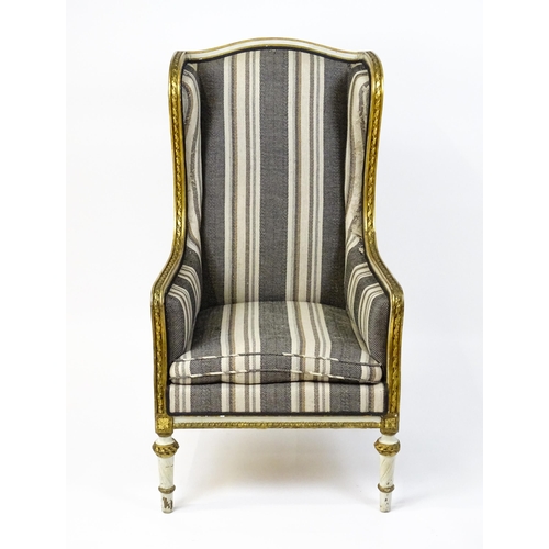 1557 - A Louis XVI style wingback armchair with a white and gold painted frame, striped upholstery and rais... 