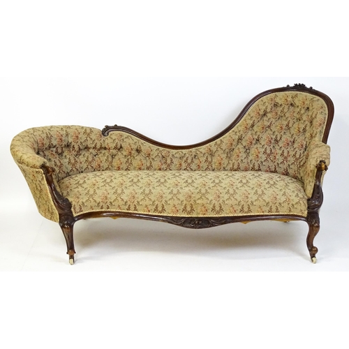 1572 - A Victorian sofa / chaise longue with a carved show wood frame and a deep buttoned backrest and spru... 