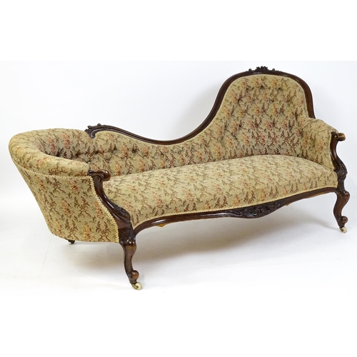 1572 - A Victorian sofa / chaise longue with a carved show wood frame and a deep buttoned backrest and spru... 