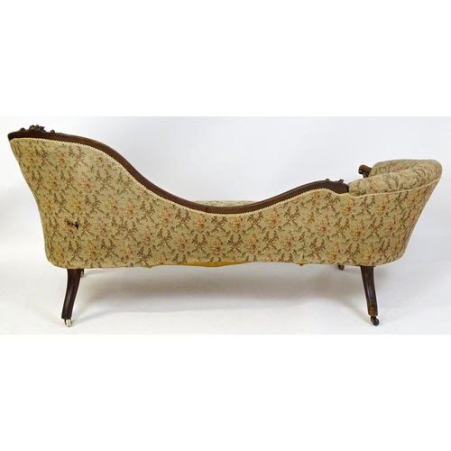 1572 - A Victorian sofa / chaise longue with a carved show wood frame and a deep buttoned backrest and spru... 