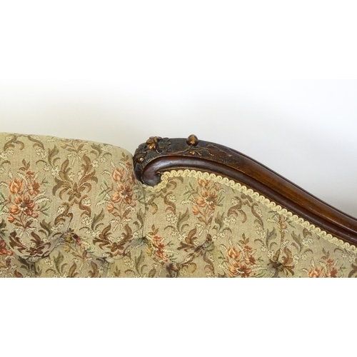 1572 - A Victorian sofa / chaise longue with a carved show wood frame and a deep buttoned backrest and spru... 