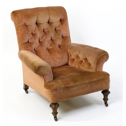 1577 - A large Victorian armchair with a scrolled backrest and arms having deep buttoned upholstery and rai... 