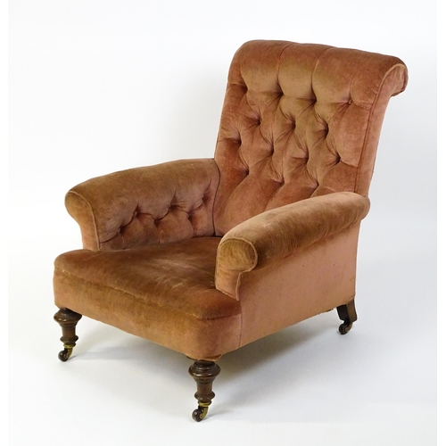 1577 - A large Victorian armchair with a scrolled backrest and arms having deep buttoned upholstery and rai... 