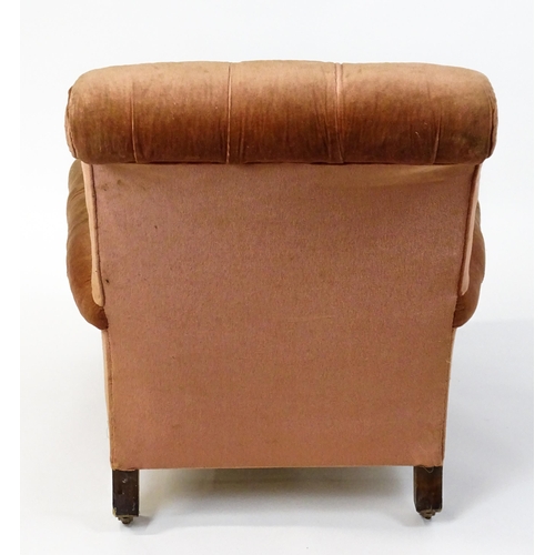 1577 - A large Victorian armchair with a scrolled backrest and arms having deep buttoned upholstery and rai... 