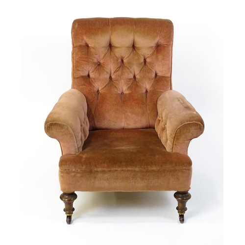 1577 - A large Victorian armchair with a scrolled backrest and arms having deep buttoned upholstery and rai... 