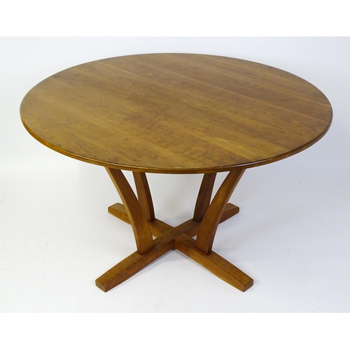 1634 - Vintage / Retro: A teak dining table with a circular top raised on four shaped supports with an x-fr... 