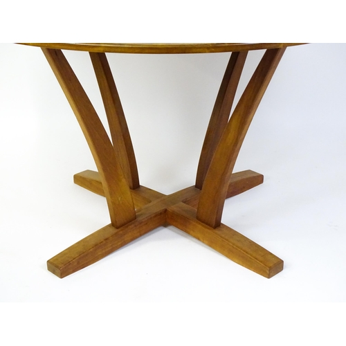 1634 - Vintage / Retro: A teak dining table with a circular top raised on four shaped supports with an x-fr... 