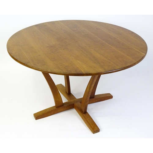 1634 - Vintage / Retro: A teak dining table with a circular top raised on four shaped supports with an x-fr... 